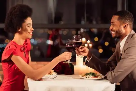 一对快乐的情侣坐在餐厅里碰杯喝红酒照片